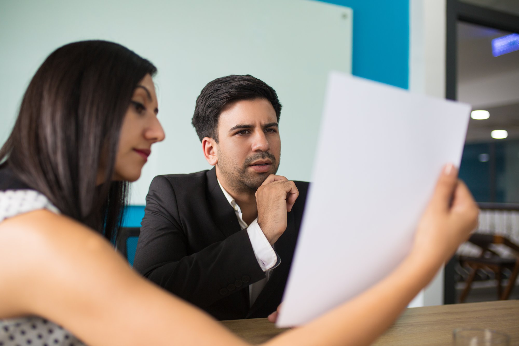 young-female-secretary-showing-document-puzzled-executive